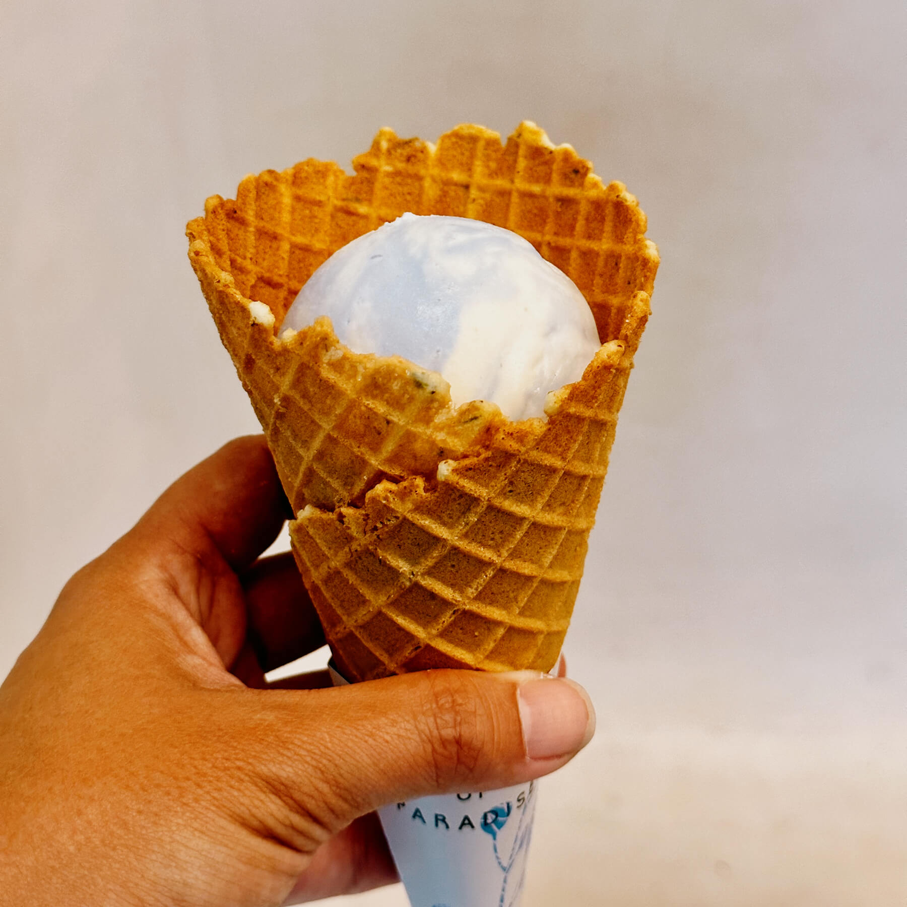 a photo of a light blue and white ice cream in a cone