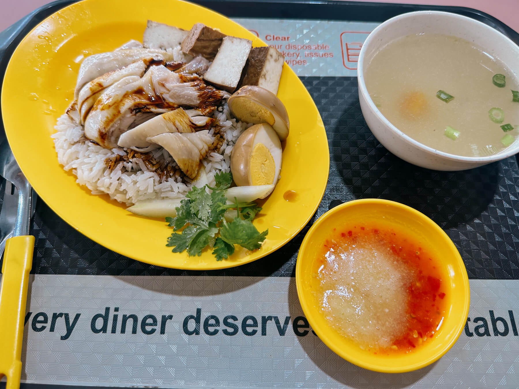 a photo of chicken rice, with condiments, on a tray