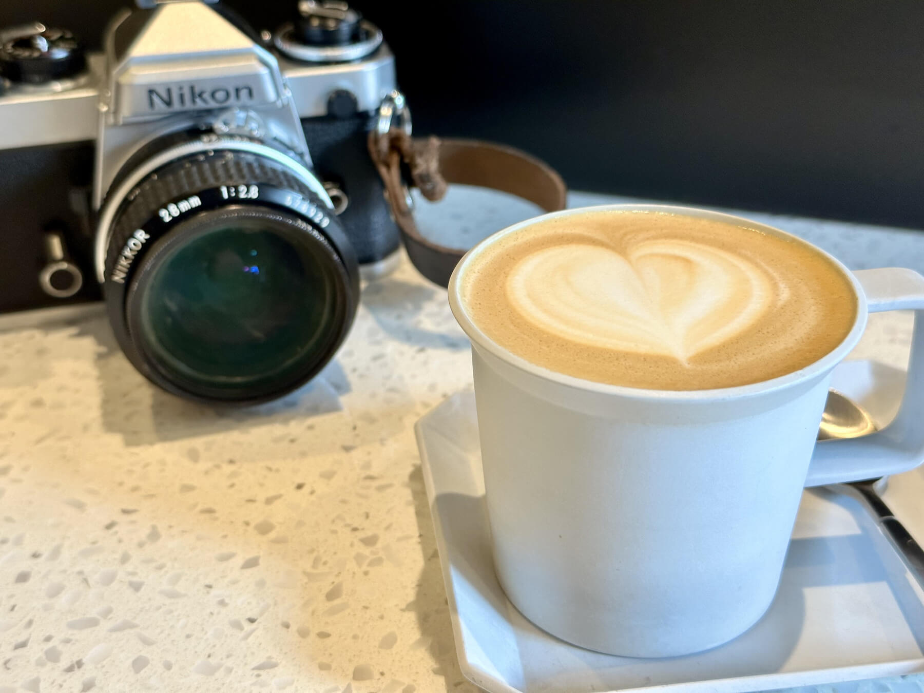 a photo of a latte, next to a nikon film camera