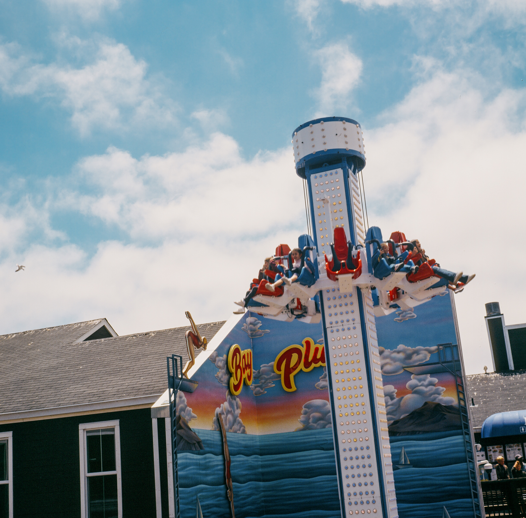 a scan of a color slide photo of a tourist atraction in san francisco. it has children sitting on a vertical amusement park ride.