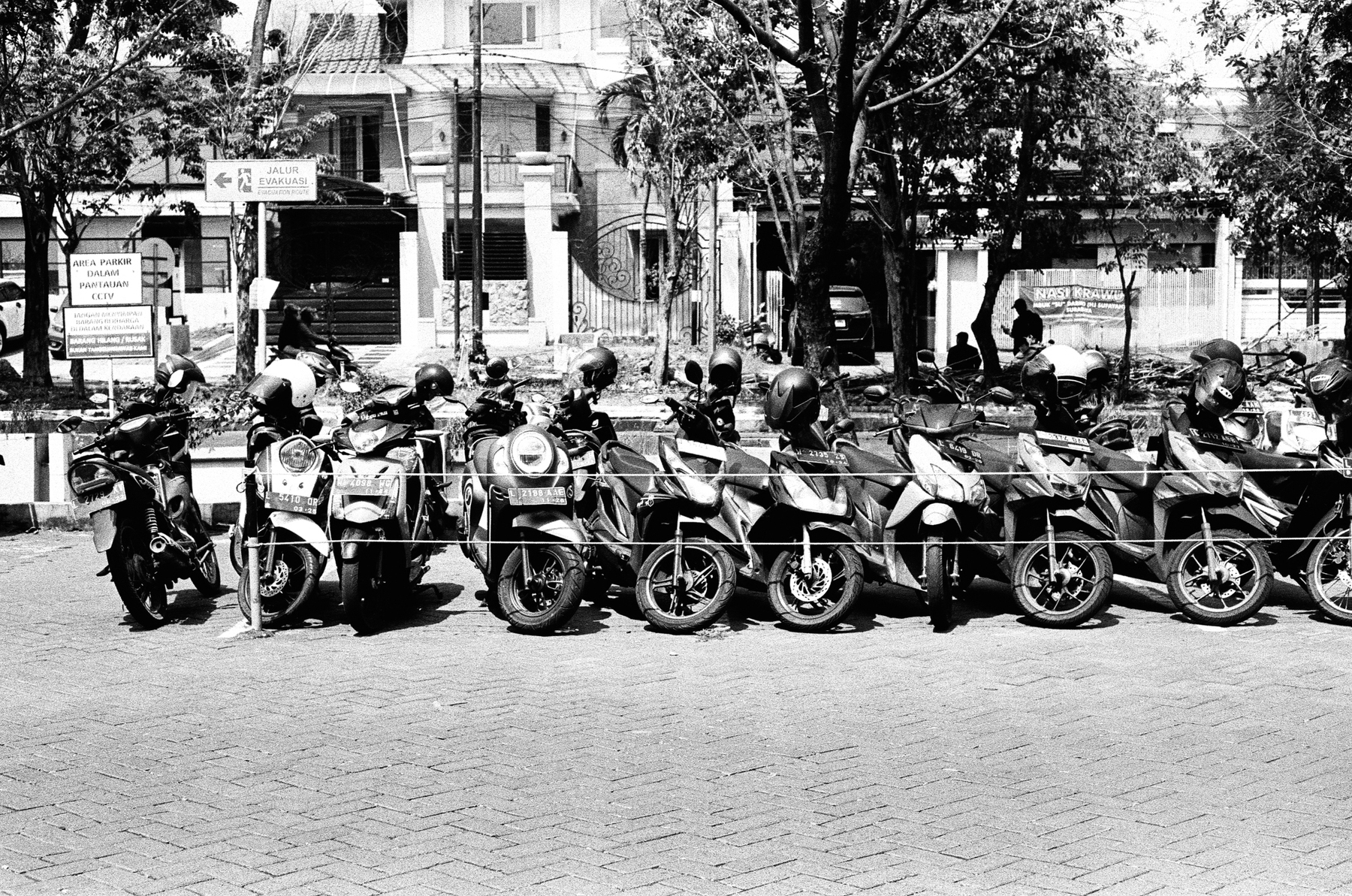 a scan of a black and white photo of dozens of motorbikes parked on the street