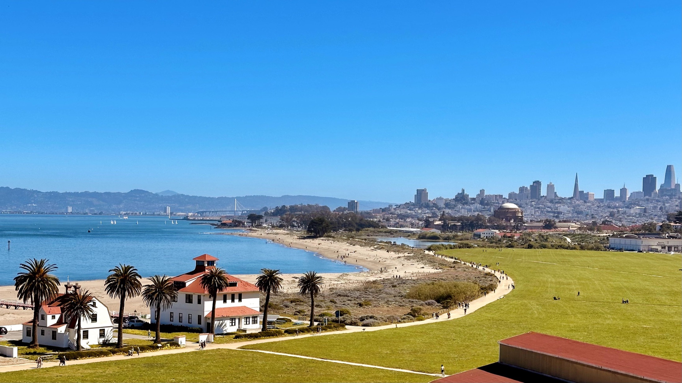 A wide view of the San Francisco skyline and bay under soft evening clouds.