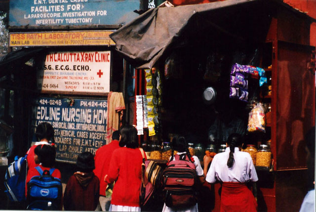 Kolkata street view with pedestrians, vehicles, and weathered facades.
