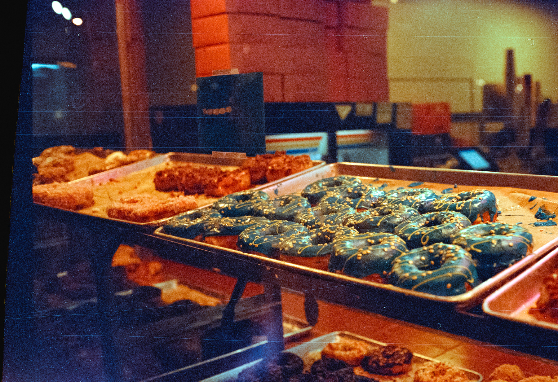 a scan of a color photograph that shows colorful donuts through a glass window