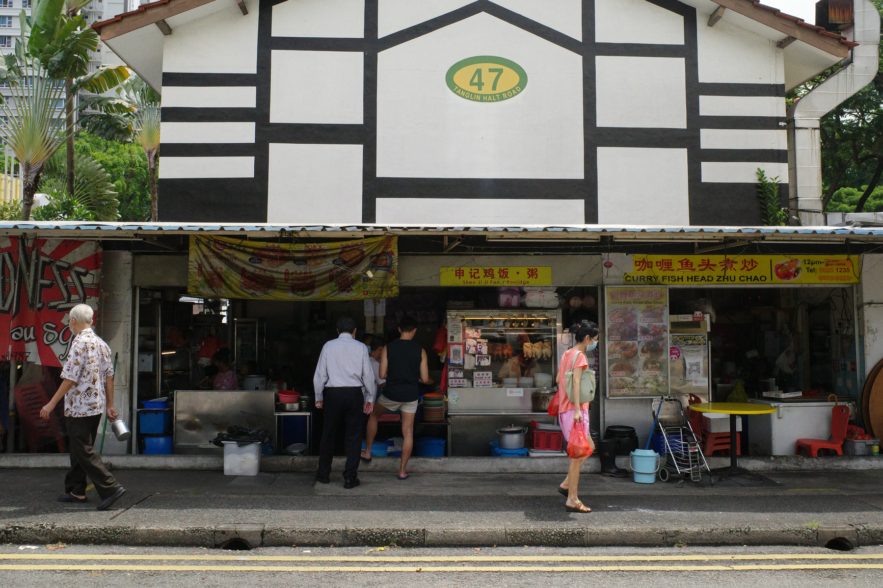 a color photograph of an old neighborhood in Singapore with people walking past food sellers in a low rise building