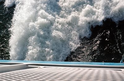 A scan of a color photograph of a ferry causing large waves in the water. View from the deck