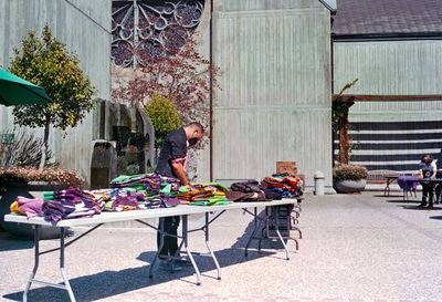a scan of a color photograph showing a volunteer managing some tables with free clothing
