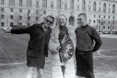 a scan of a black and white photo showing a few smiling people attending the drag and trans rally