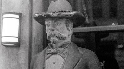 a scan of a black and white photo showing a stone statue of a man outside an Irish bar in San Francisco