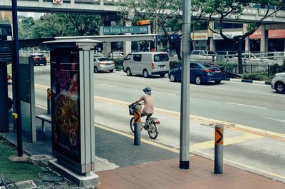 A scan of a color photo of an old lady cycling on the street in Chinatown