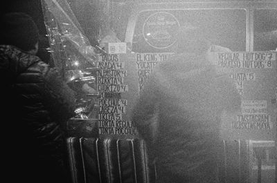 a scan of a black and white photo showing a few people ordering tacos from a street taco vendor