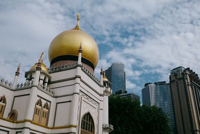 a color photograph showing a large mosque with an ornate dome. in the background, some tall concrete buildings.