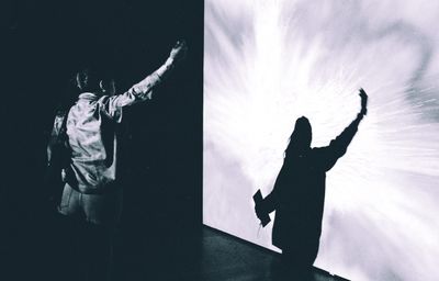 Two silhouettes against a bright backlit background, dramatic and moody