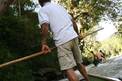 a color photograph of a person rowing a longtail boat