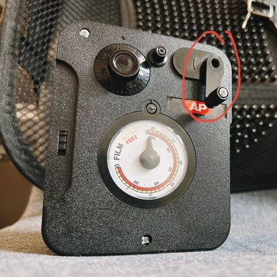 a photo of the front view of a film bulk loader with an arrow over the spindle