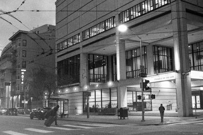 a scan of a black and white photograph of a person crossing a street in front of UC Law in San Francisco Civic Center
