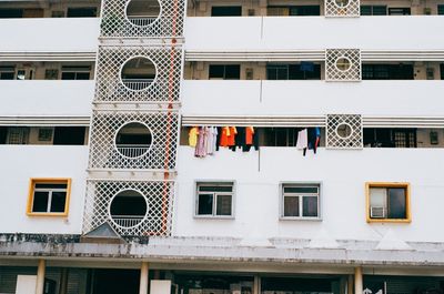 a scan of a color photo of some yellow work shirts being hung from the side of a tall building