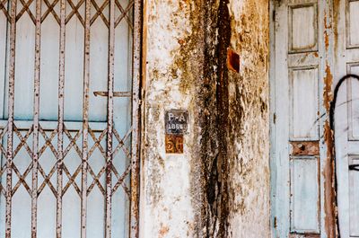 a scan of a color photo showing an old pale blue door and dirty cement and metal bars