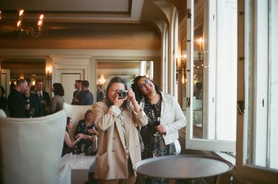 a color photograph of a queer couple taking a photo in a mirror with a film camera in San Francisco in a gala-like setting with formal attire